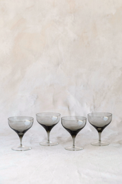 Set of four Hoppe Shoppe vintage crystal coupe glasses featuring smoky charcoal bowls and clear stems.