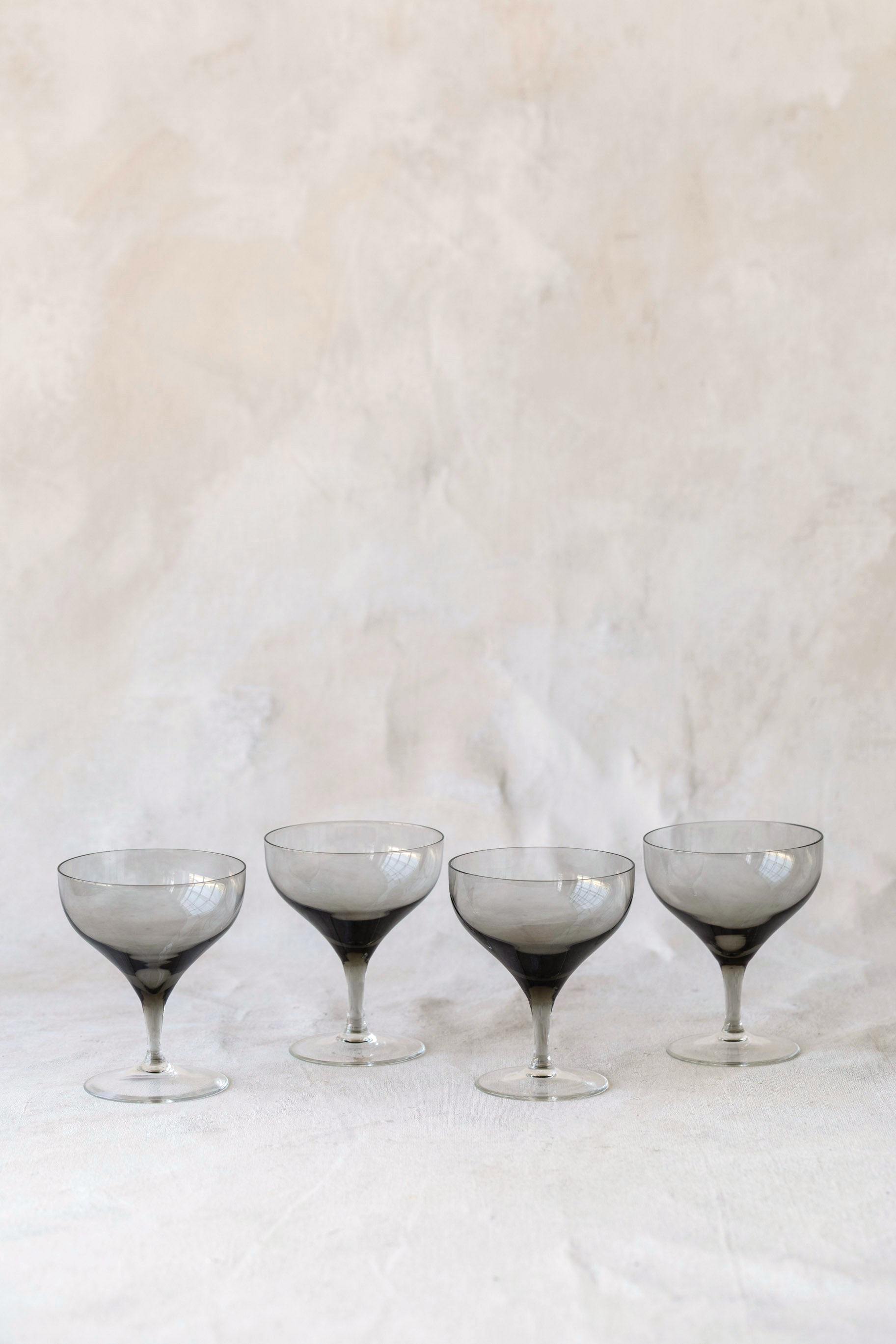 Set of four Hoppe Shoppe vintage crystal coupe glasses featuring smoky charcoal bowls and clear stems.