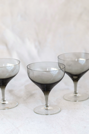 Hoppe Shoppe set of three vintage crystal coupe glasses with smoky charcoal bowls and clear stems on a white cloth.